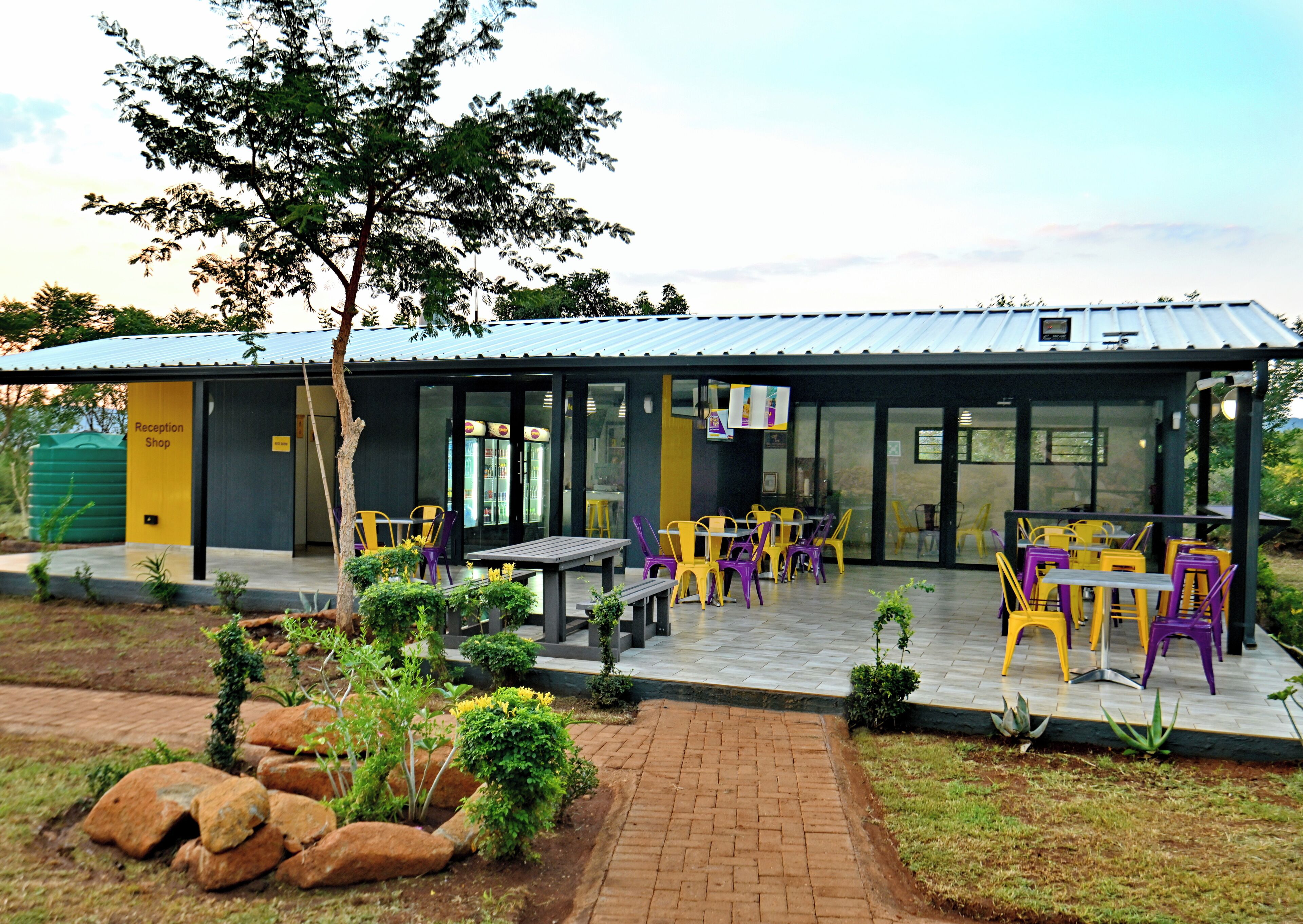 A reception area with a shop, outdoor seating with tables and chairs, and a garden with rocks and plants.