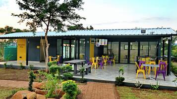 A reception area with a shop, outdoor seating with tables and chairs, and a garden with rocks and plants.