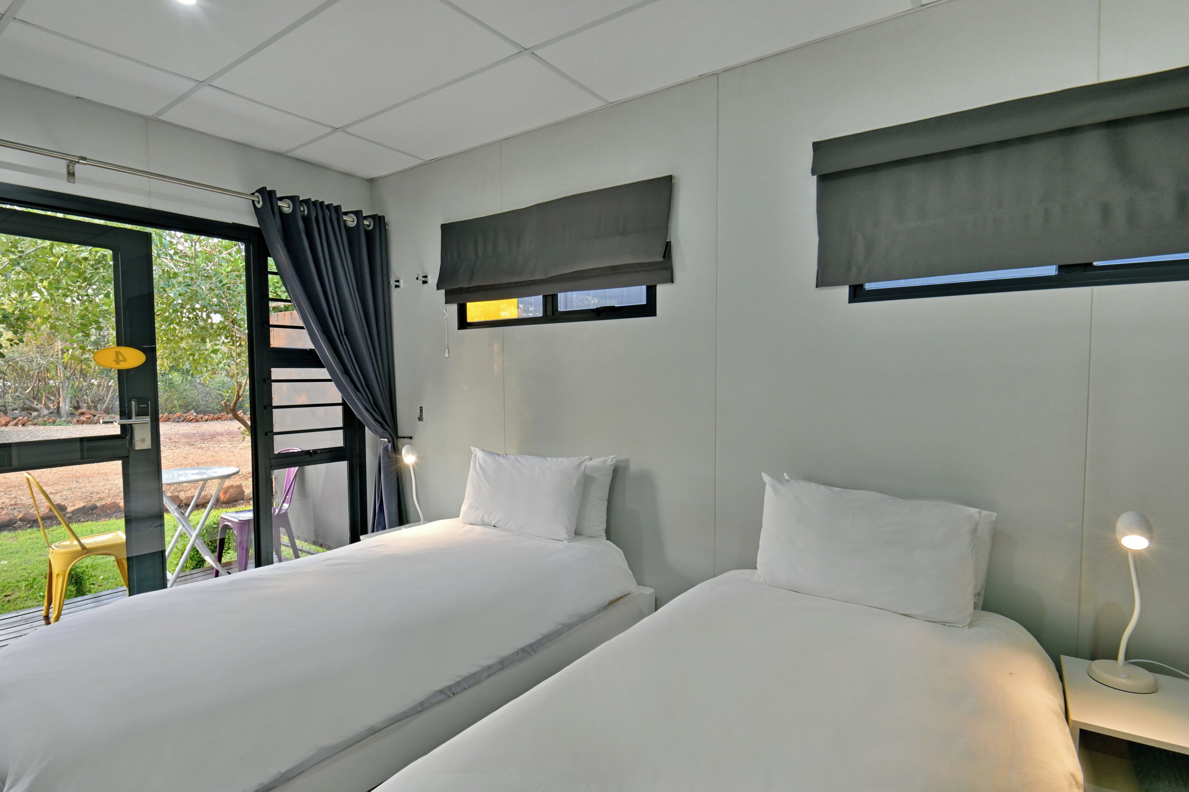 A hotel room with two beds, a window with a view, a small table, and a chair.
