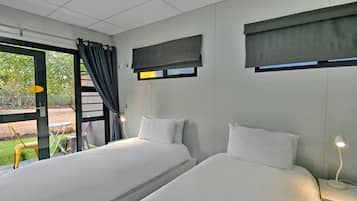 A hotel room with two beds, a window with a view, a small table, and a chair.