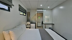 A hotel room with a bed, a desk, a chair, a small kitchenette, and a bathroom. - SleepOver Punda Maria  (Thulamela)