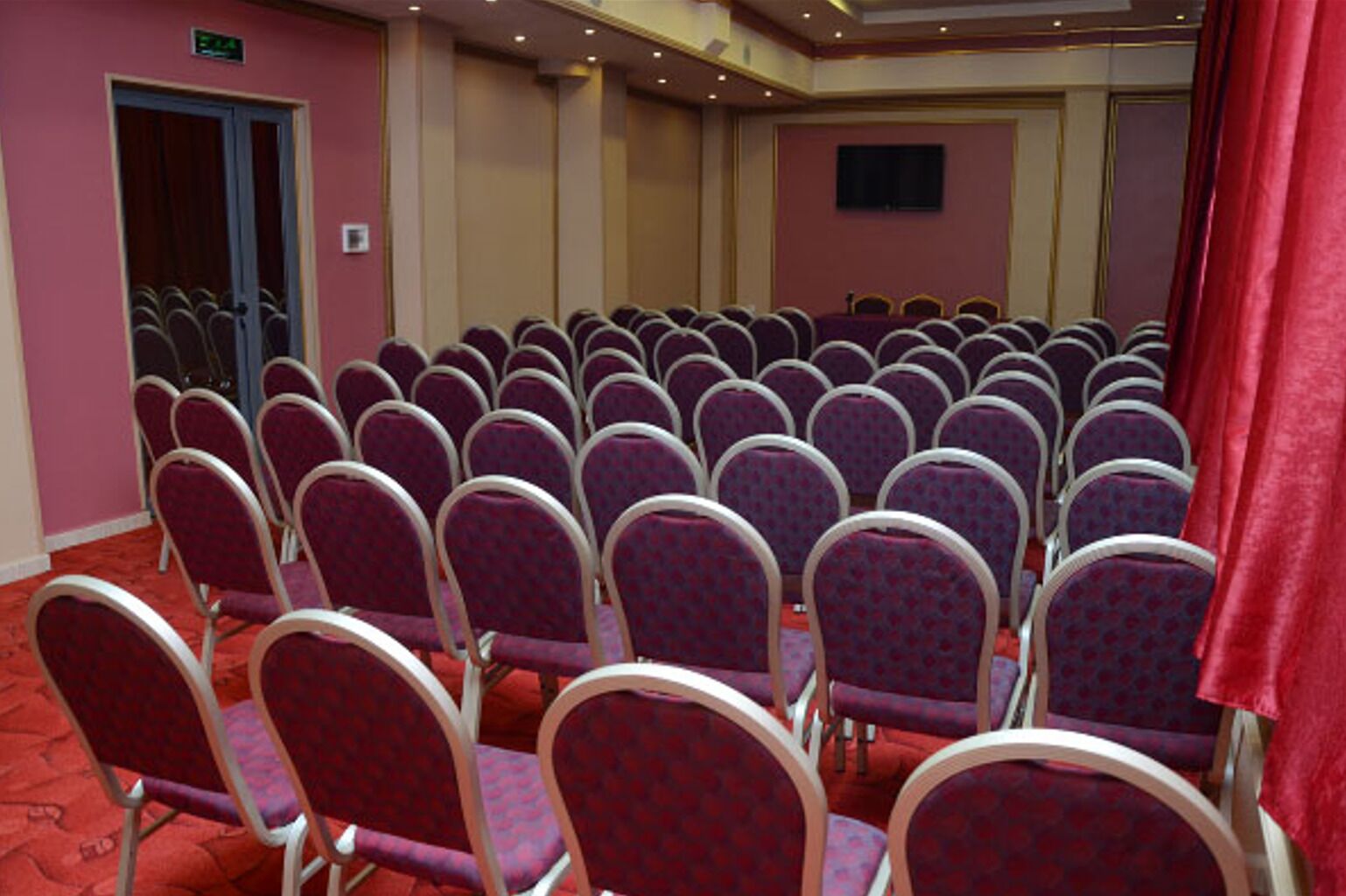 Un salón de conferencias con filas de sillas moradas y una alfombra roja.