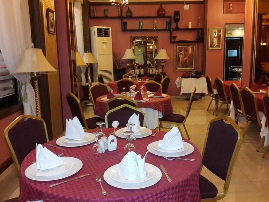 Comedor con mesas redondas dispuestas para cuatro, cada una con platos blancos, servilletas dobladas y cubiertos.