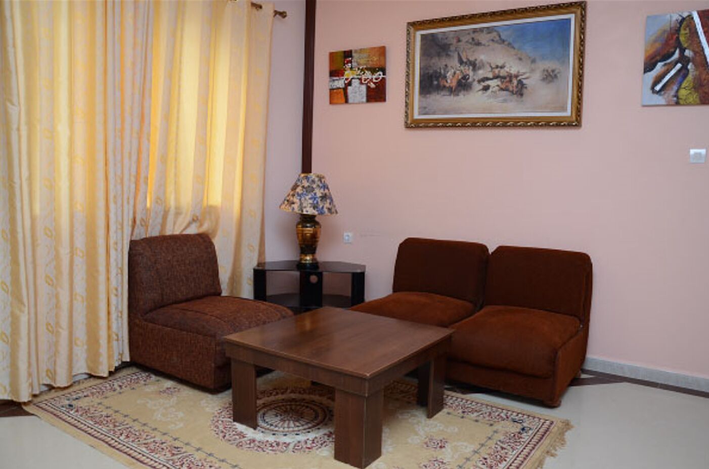 A living room with a sofa set, a coffee table, a lamp, and a painting on the wall.