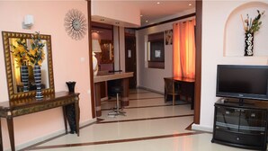 A spacious living area with a large flat-screen TV, a dining table, and a decorative mirror. - Ambassadeurs Oran (Oran)