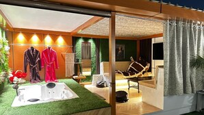 A modern spa room with a jacuzzi, two robes, a massage chair, and a large window with curtains. - Desire Stay (New Delhi)