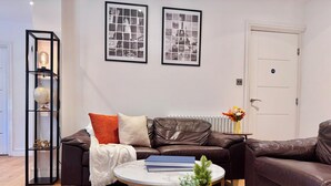 Een woonkamer met een bruine leren bank, een witte ronde salontafel en een wereldbol op een zwart schap.