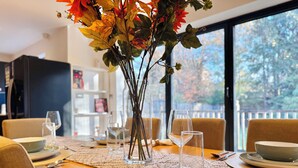 A dining table set with plates, bowls, cutlery, and a vase with flowers. - Family-Friendly En-suite 30min to Central London (Wembley)