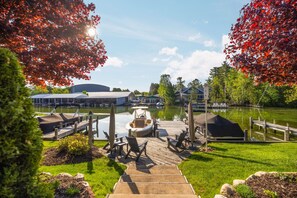 A dock with a boat, outdoor seating, and a building in the background.
