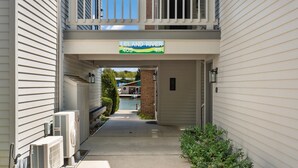 A corridor with a sign indicating Leland River, numbers 409 and 411, leading to a building with a balcony and outdoor area.