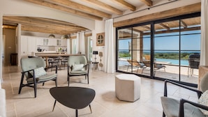 Un vaste espace de vie avec une grande porte-fenêtre coulissante donnant sur un balcon avec vue sur la piscine.