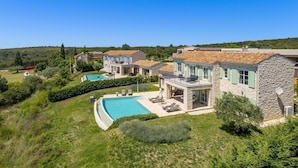 Une grande maison en pierre dotée d’une piscine et de plusieurs balcons.