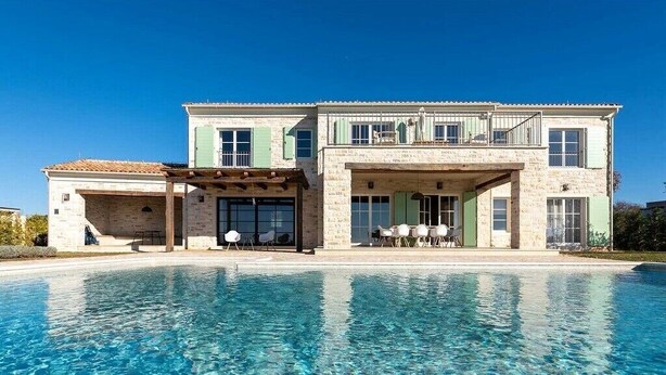 Une maison à deux étages avec une piscine devant.