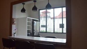 A kitchen with a large window, a white countertop, and black chairs.
