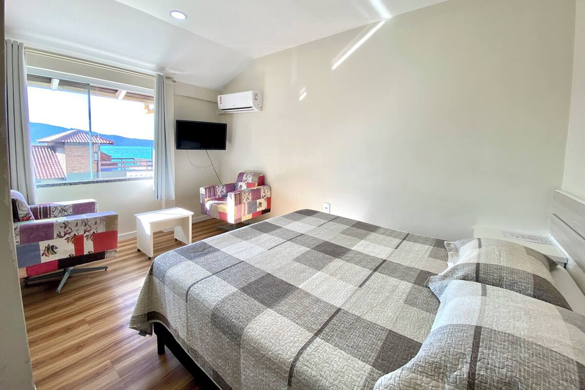 A bedroom with a bed, a small table, a sofa, and a TV.