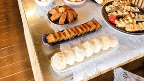 Buffet com diversos alimentos, incluindo pães, doces e sobremesas.