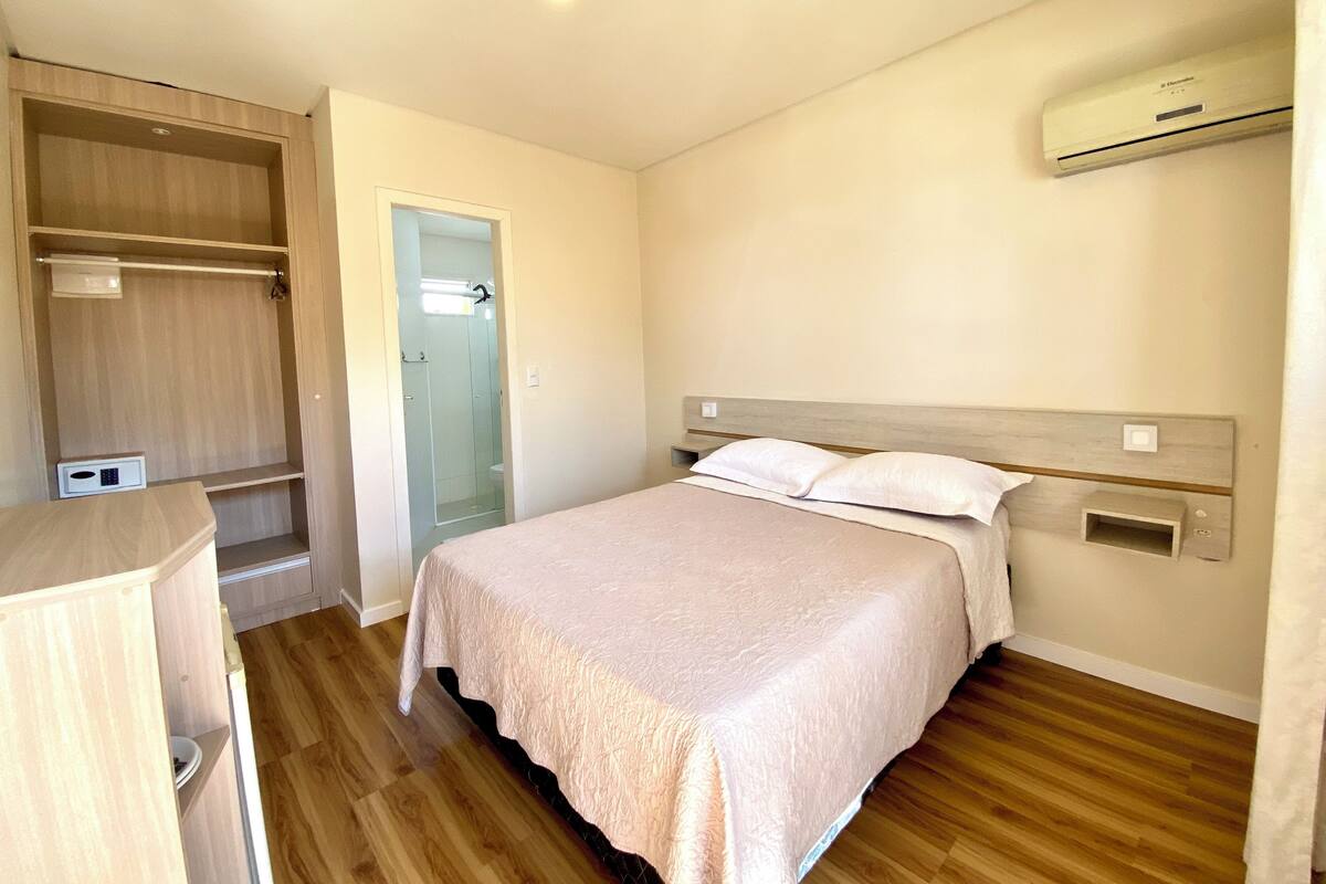 A bedroom with a bed, a wardrobe, a shower, and an air conditioning unit.