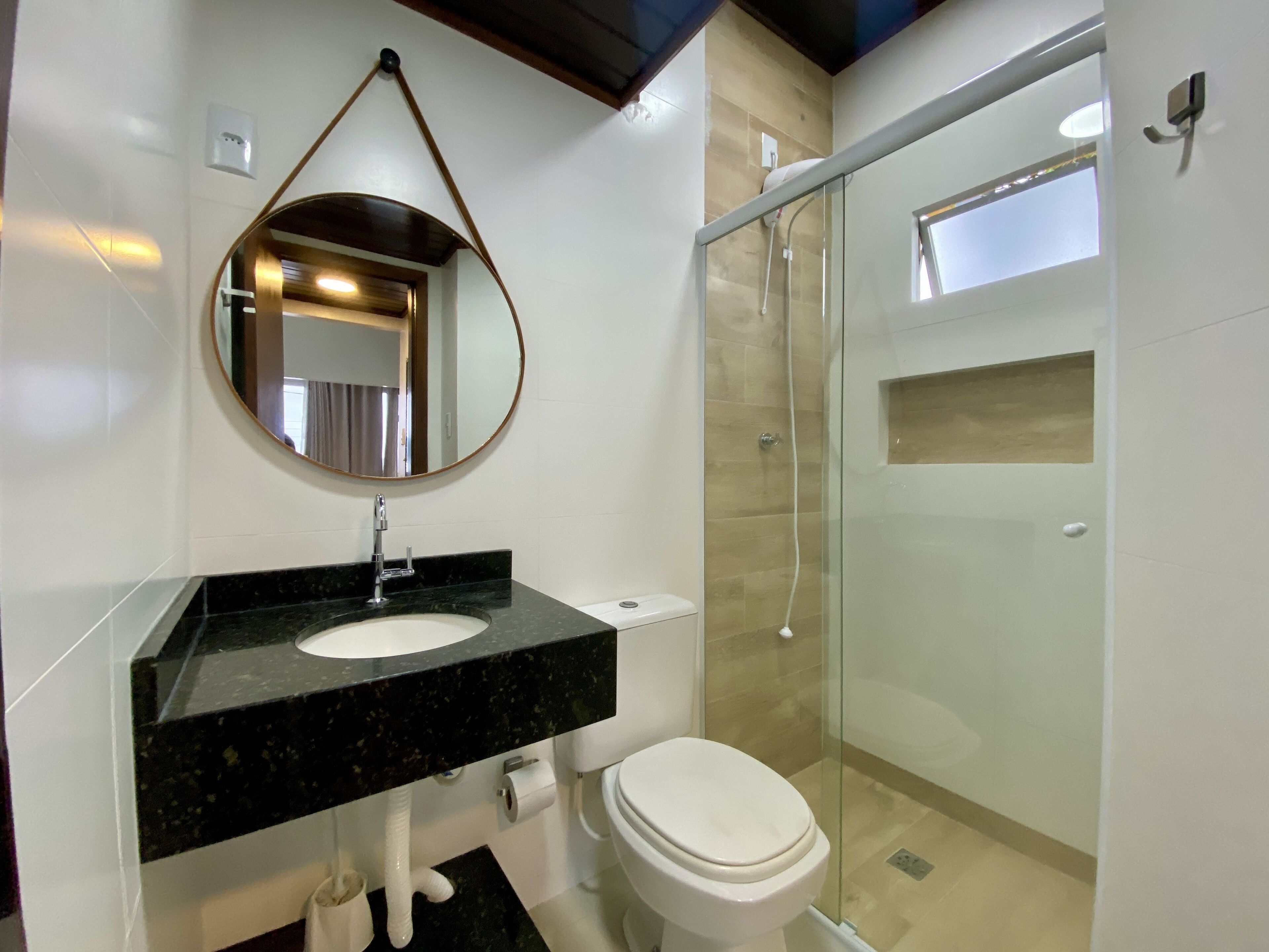 A modern bathroom with a black marble sink, a white toilet, and a glass-enclosed shower.