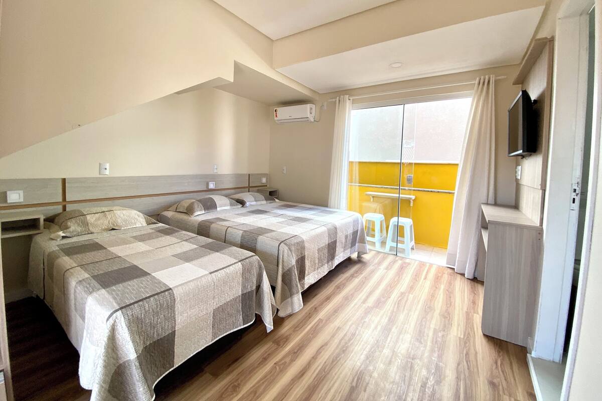 A hotel room with two beds, a small table, and a TV.