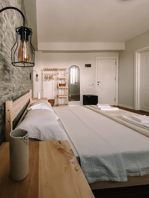 A bedroom with a large bed, a wooden nightstand, a mirror, and a wardrobe. - Vinea Bozcaada (Bozcaada)