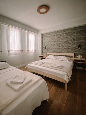 A bedroom with two beds, a stone wall, and a wooden floor. - Vinea Bozcaada (Bozcaada)