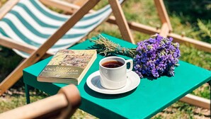 A green table with a book, a cup of coffee, and a bouquet of purple flowers. - Vinea Bozcaada (Bozcaada)
