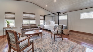 A bedroom with a four-poster bed, a sofa, a coffee table, and a chair.