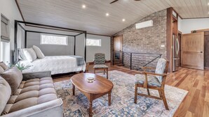 A spacious living area with a high ceiling, a fireplace, a dining table, and a comfortable seating arrangement.