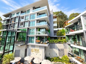 A multi-story building with balconies, outdoor seating, and a sign indicating it is a condominium.