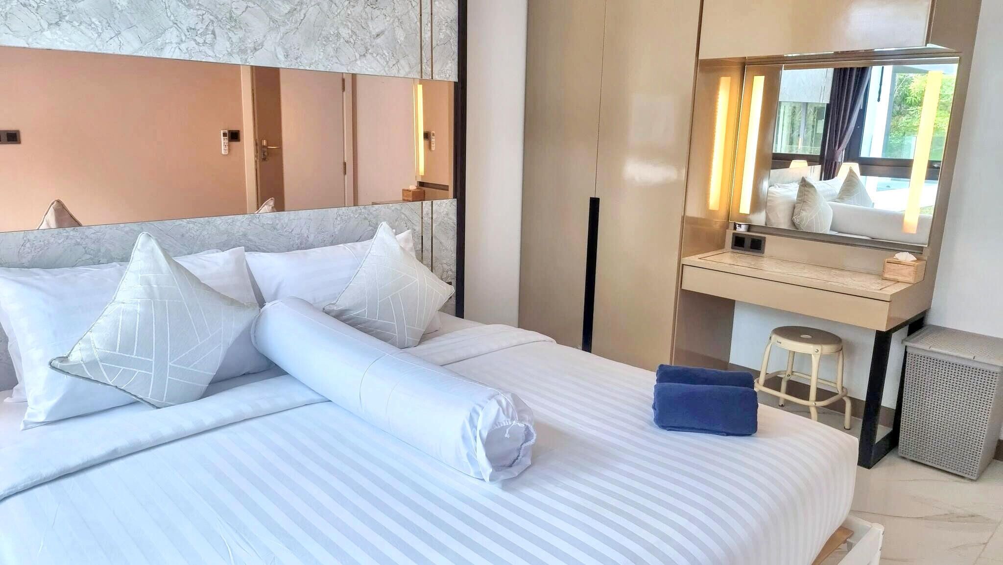 A hotel room with a bed, a desk, a mirror, and a window.