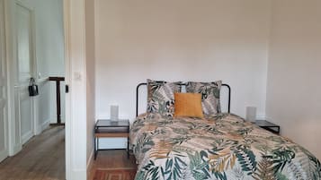 A bedroom with a bed, a nightstand, a lamp, and a hanging light fixture.