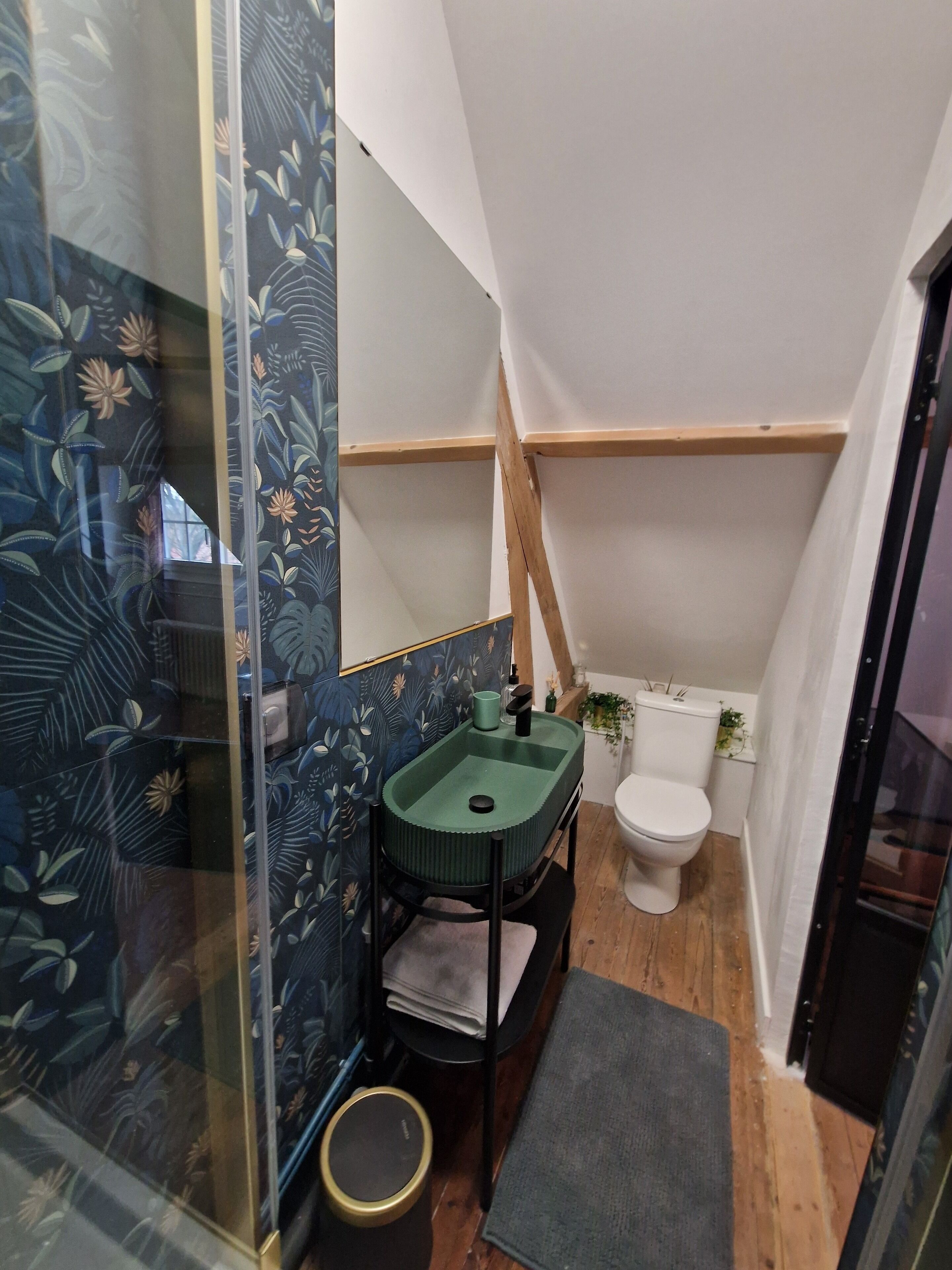 A bathroom with a green sink, a toilet, and a shower area.