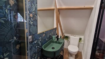 A bathroom with a green sink, a toilet, and a shower area.