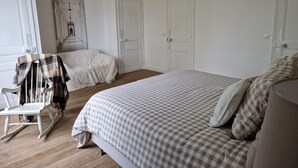 A bedroom with a large bed, a rocking chair, and a door. - Demeure du saule Madame (Thieux)