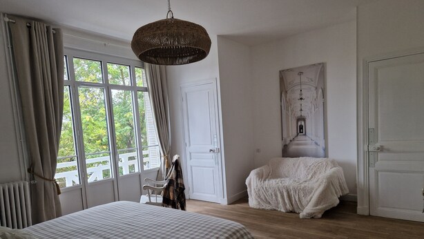 A bedroom with a large bed, a chair, a wardrobe, and a view through a window. - Demeure du saule Madame (Thieux)