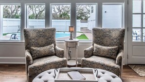 A room with two patterned armchairs, a small side table with a lamp, and a tufted ottoman with a tray. - Coastal Oasis - Beautiful Ocean Views Awaits (Corpus Christi)