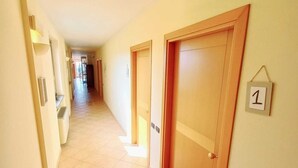 A hallway with tiled flooring, wooden doors, and a number sign indicating room 1. - LOCANDA DEL VIANDANTE (Magliano Alfieri)