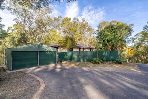 A residential property with a green garage, a fenced yard, and a road sign indicating a 30 km/h speed limit.