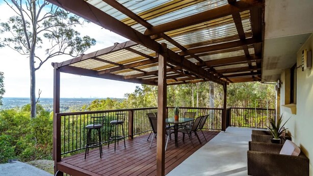 Un espace extérieur abrité, doté d’une terrasse en bois, d’une rambarde en métal et de sièges.