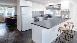 Une cuisine moderne avec des meubles blancs, un plan de travail en granit et un îlot central intégré doté de tabourets de bar.