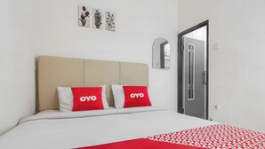 A hotel room with a bed, two red pillows with "OYO" branding, a white and red bedspread, and a door with a mirror and a window. - OYO 93720 3D Residence Near Univ. Tarumanegara (Jakarta)