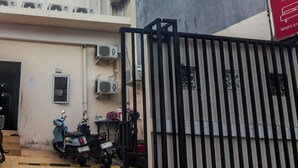 A multi-story building with air conditioning units, a gated entrance, and parked scooters. - OYO 93720 3D Residence Near Univ. Tarumanegara (Jakarta)