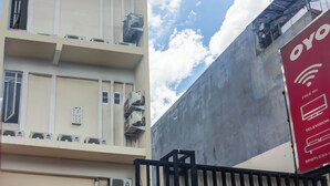 A multi-story building with air conditioning units on the exterior, a red sign advertising free Wi-Fi, television, and spotlessness. - OYO 93720 3D Residence Near Univ. Tarumanegara (Jakarta)