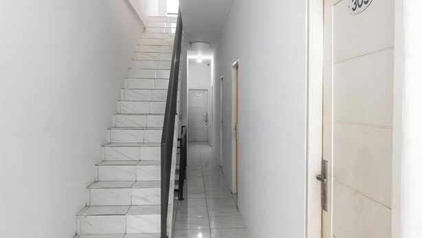 A staircase with white marble steps and a black handrail, leading to a door with the number 303. - OYO 93720 3D Residence Near Univ. Tarumanegara (Jakarta)