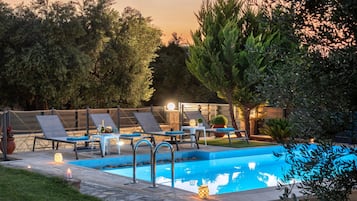 En sÀsongsöppen utomhuspool, parasoller och solstolar