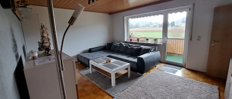 Un salon avec un canapé gris, une table basse blanche et un plafond en bois.