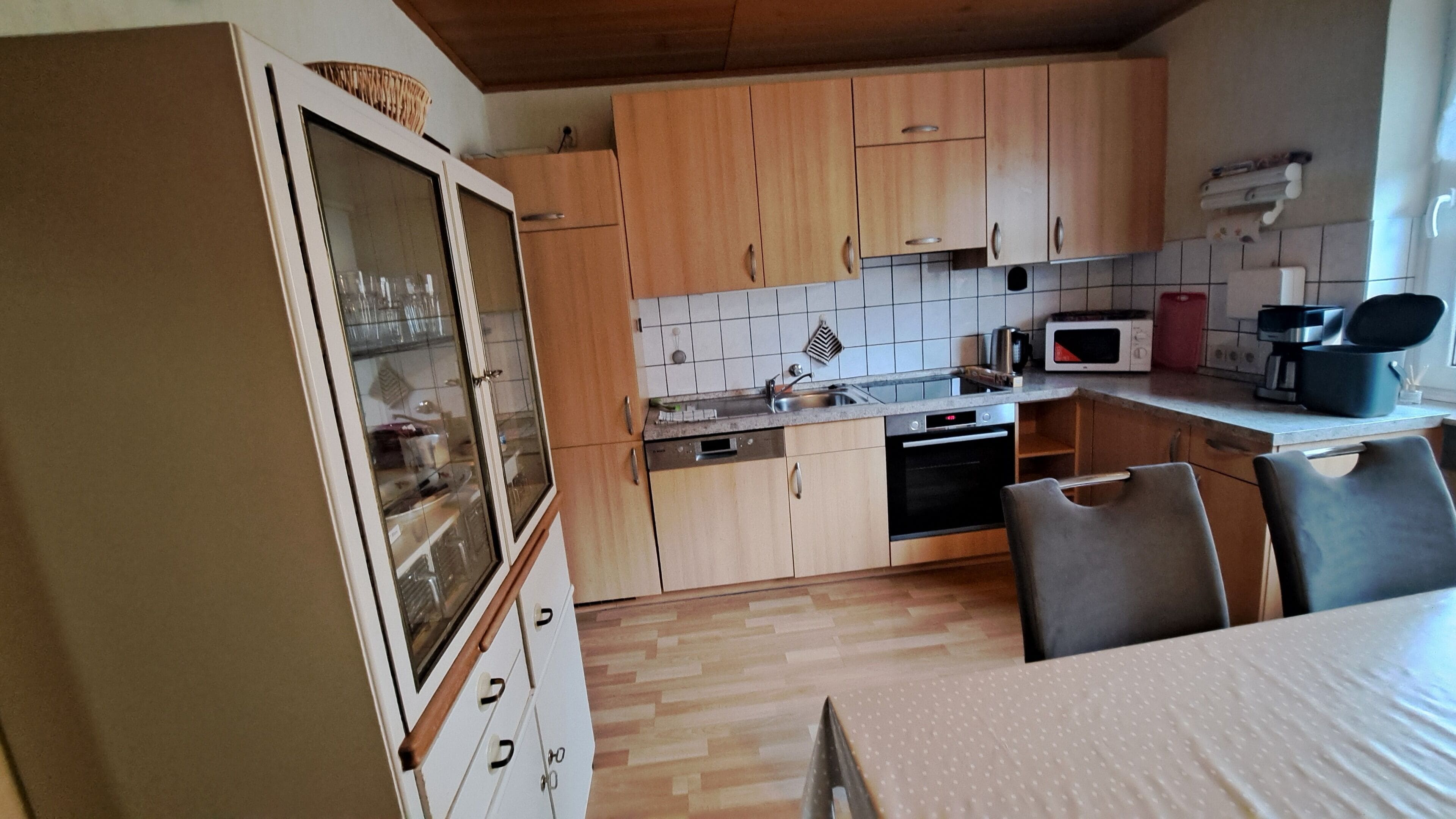 A kitchen with wooden cabinets, a microwave, a dishwasher, and a dining table with chairs.