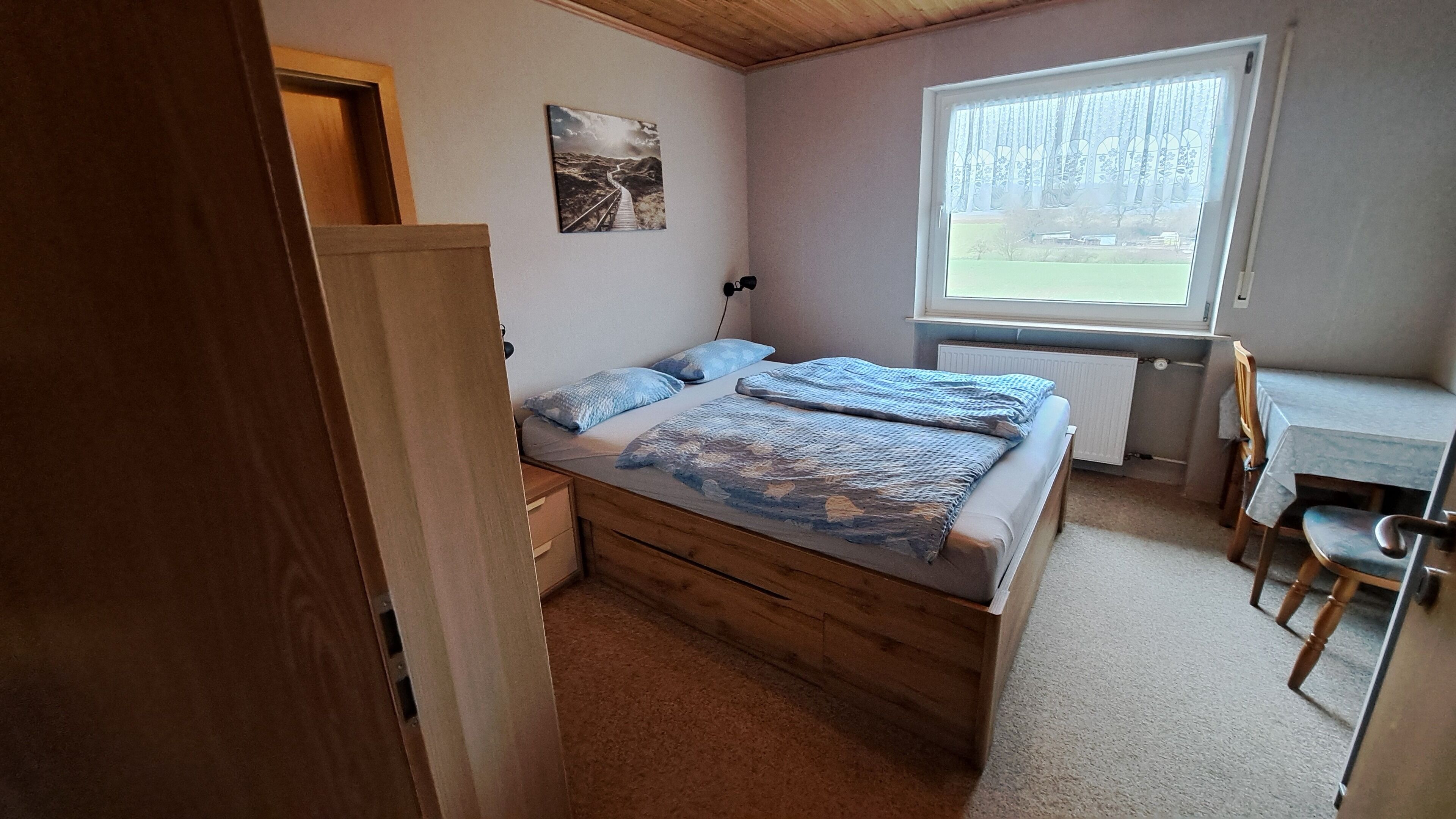 Un dormitorio con cama de madera, un escritorio y una silla.