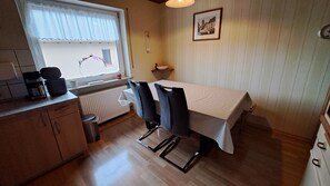 A small kitchen with a dining table, chairs, a coffee maker, and a radiator. - Vacation Apartment in the Heart of Franconia (Winterhausen)
