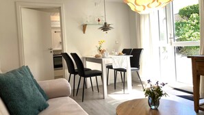 Un salon moderne avec un canapé, une table à manger et des chaises, et une cuisine en arrière-plan.
